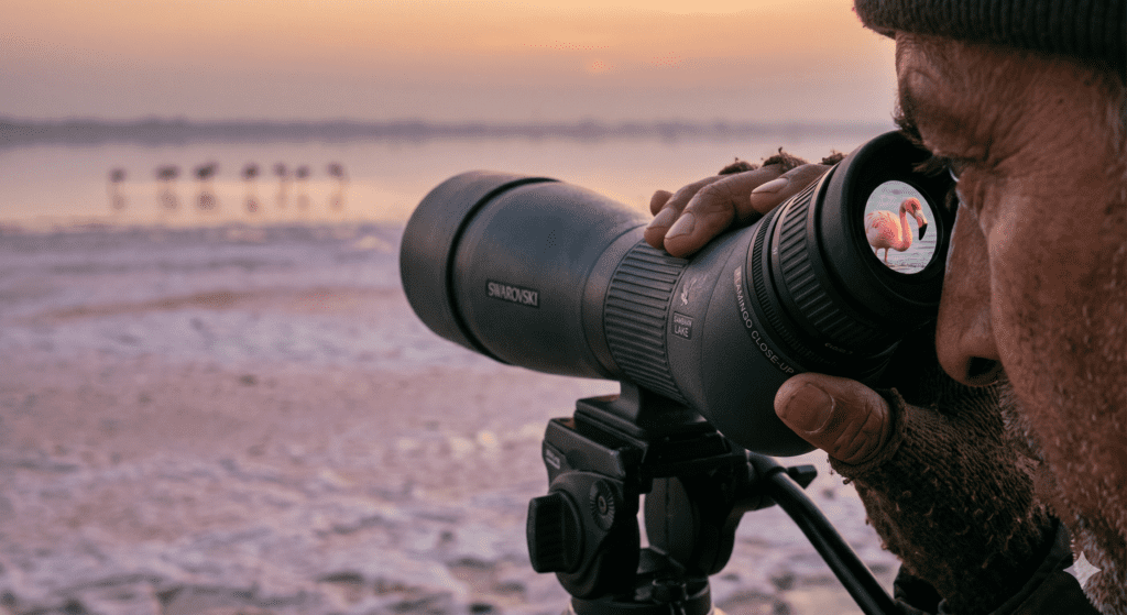 a man standing with camera in sambhar lake taking picture of birds 