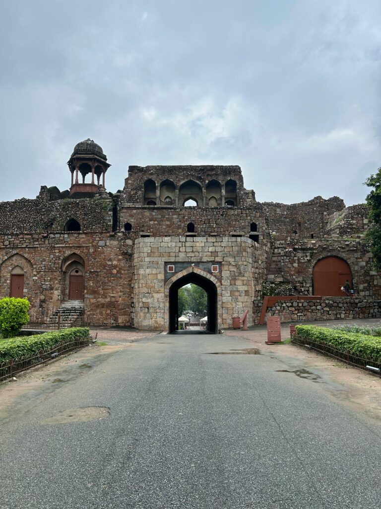 Stone entrance of the historic Purana Qila in Delhi, India, under a cloudy sky.